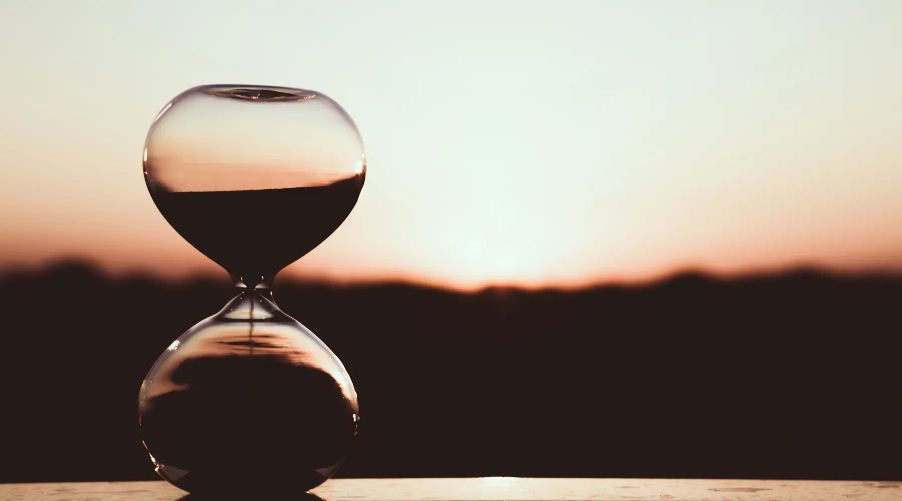 Hourglass with a sunset in the background depicting how long do supplements take to work