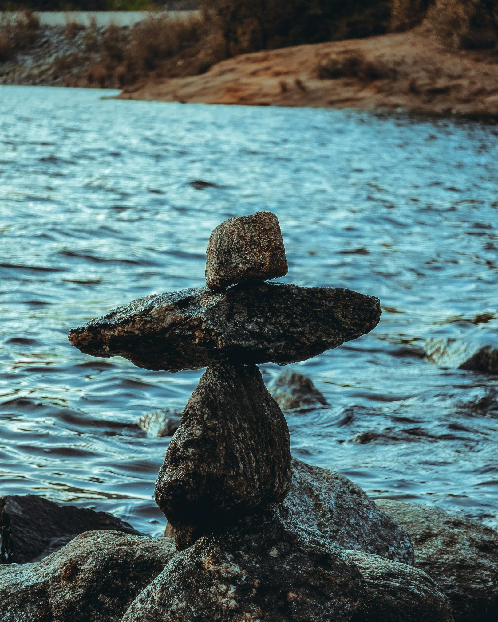 Stack of stones balanced on a rock by a body of water